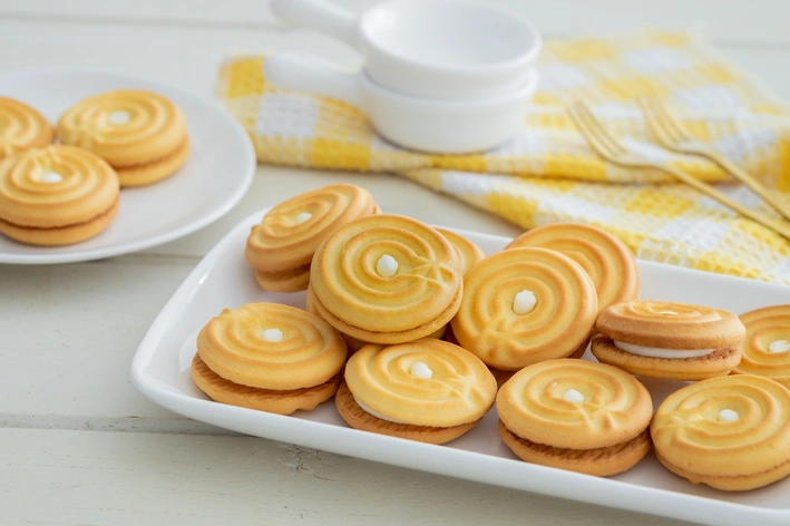 Deliciosas bolachas recheadas com creme servidas em uma travessa branca, perfeitas para café da tarde ou momentos de lazer.