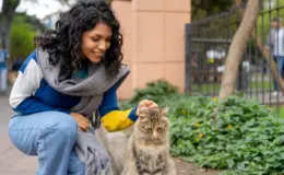 Mulher fazendo carinho em um gato de rua.