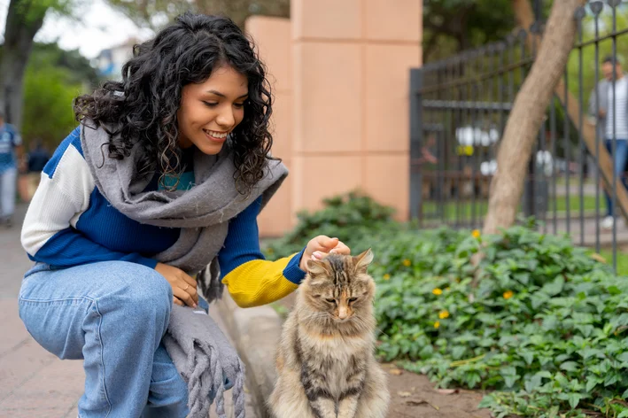 Mulher fazendo carinho em um gato de rua.