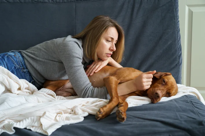 cachorro com dor de barriga ao lado da tutora