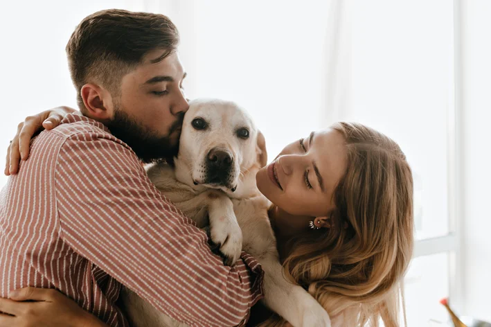 casal beijando um cachorro