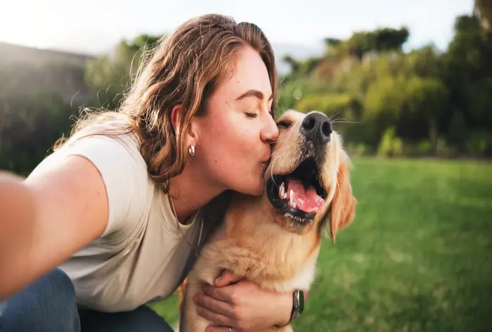 tutora beijando cachorro e tirando foto