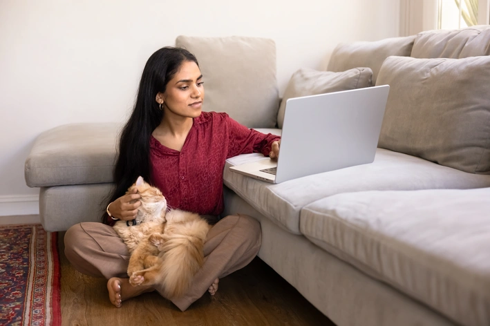 tutora mexendo no notebook enquanto o seu pet está no colo