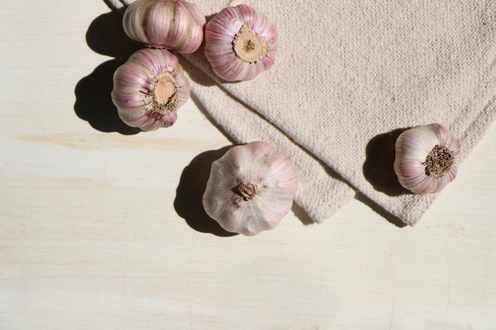  
Alho inteiro sobre uma tábua de madeira.