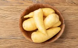 Imagem de mandioquinha em tigela de madeira sobre mesa de madeira rústica, destacado por sua textura e cor clara.