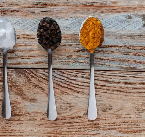 três tipos de temperos diferentes em colheres em cima de uma mesa de madeira