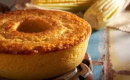 bolo de fubá em uma mesa com espigas de milho