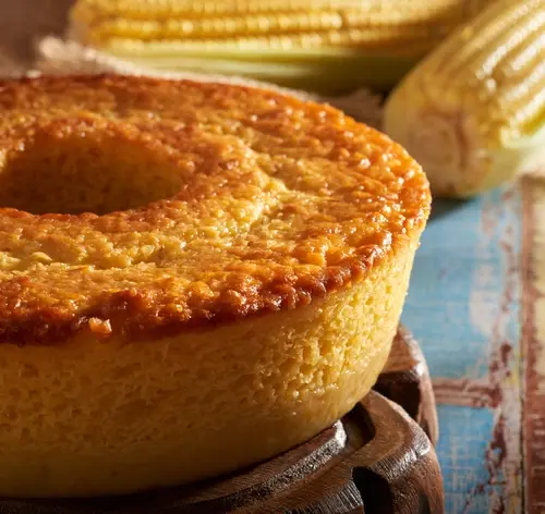 bolo de fubá em uma mesa com espigas de milho